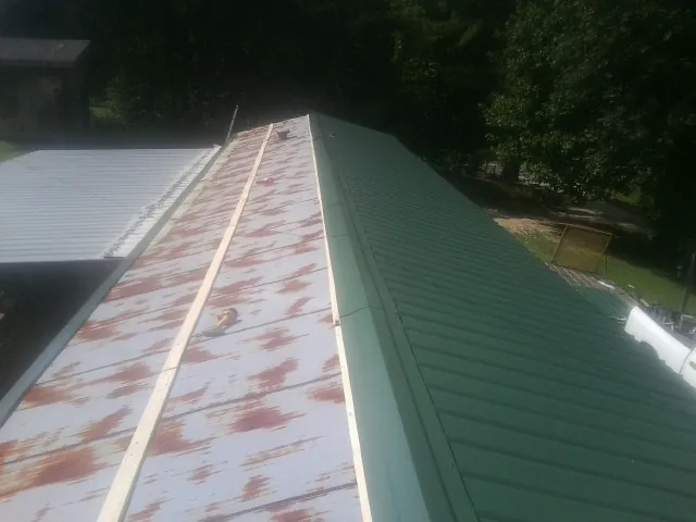 Old rusted panels beside newly installed green metal roofing — Wind Damage Roof Repair by Roofing Brothers in Buffalo Prairie