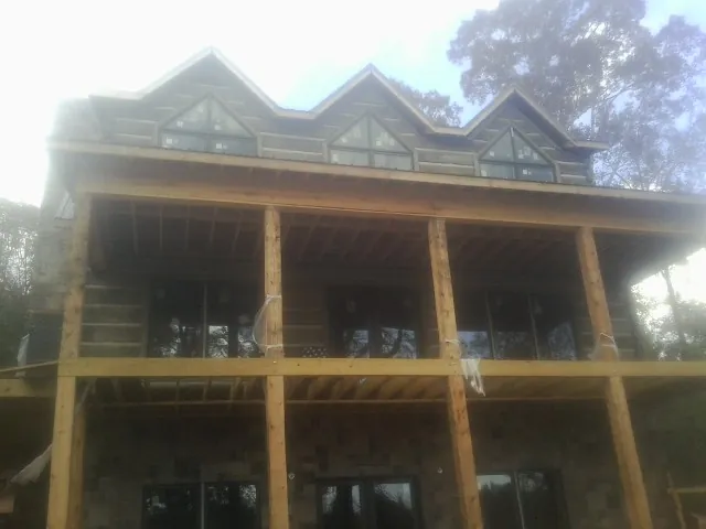 Dormers and porch framing on a large log home under construction — Roof Coating work by our crew in Buffalo Prairie