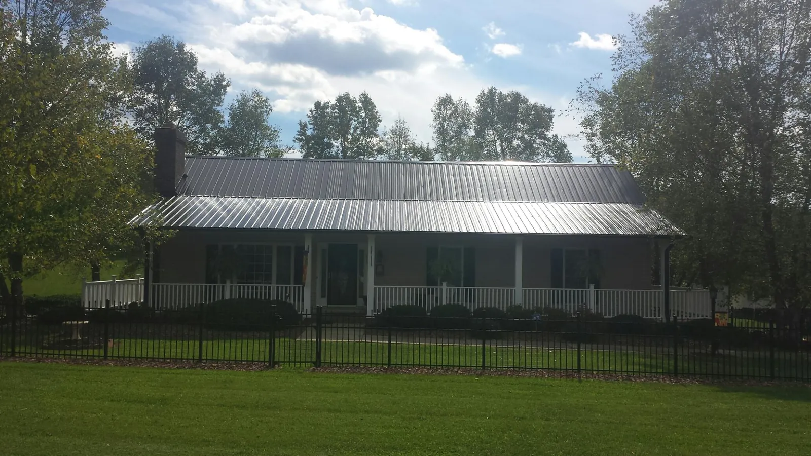 Gray metal roof on a brick ranch with a full width front porch — Gutter Guard Installation work by our crew in Buffalo Prairie