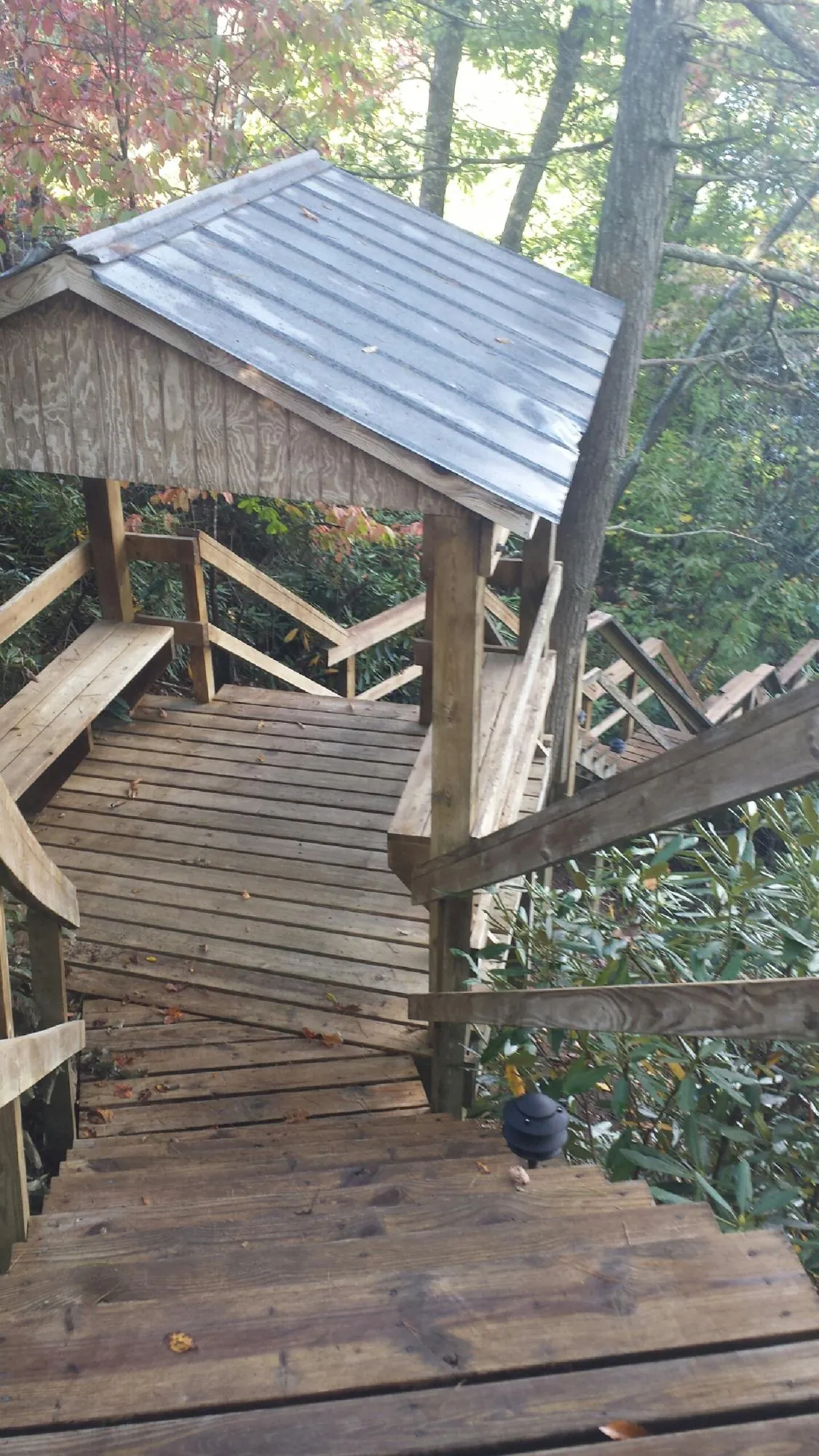 Metal roofed shelter over wooden steps on a wooded walkway — Skylight Repair & Installation work by our crew in Buffalo Prairie