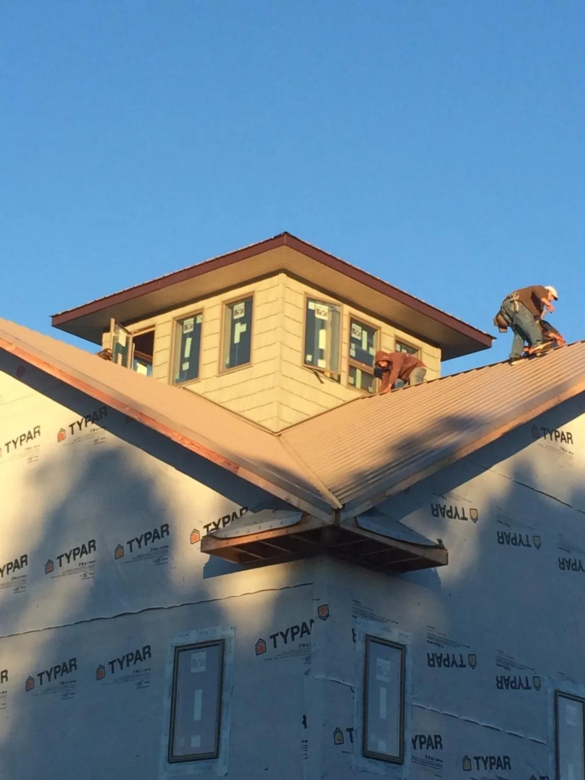 Roofers working around a rooftop cupola on a new metal roof at sunset — Roof Waterproofing in Buffalo Prairie by Roofing Brothers